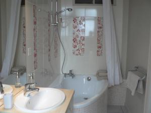 La salle de bains est pourvue d'une baignoire, d'un lavabo et d'une douche. dans l'établissement La Terrasse de la Grand'Rue - chambre d'hôtes -, à Mugron