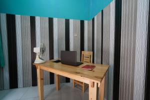 a wooden desk with a laptop and a lamp on it at Hotel O Jati Guest House in Cirebon