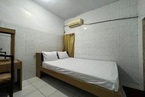 a small bedroom with a bed and a desk at Hotel O Kost Aisyah Near Citra Grand Galesong City(Pattalassang) in Bilibili