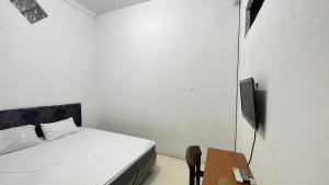 a bedroom with a bed and a table with a television at Hotel O Kost Biru in Makassar
