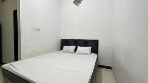 a white bed with two pillows on it in a room at Hotel O Kost Biru in Makassar