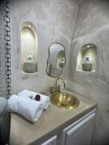 baño con lavabo de oro y espejo en Mini Style Riad in the heart of the Medina, en Essaouira