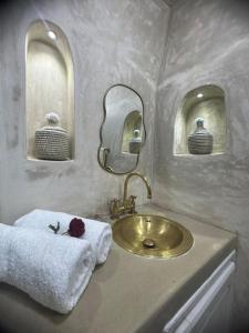 Un baño con un lavabo dorado y dos espejos. en Mini Style Riad in the heart of the Medina, en Essaouira