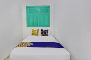 Cama en habitación blanca con ventana verde en Hotel O Karomah Kostel Syariah, en Semarang