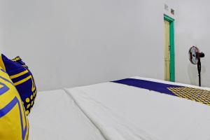 Una cama blanca con una almohada azul y amarilla. en Hotel O Karomah Kostel Syariah, en Semarang
