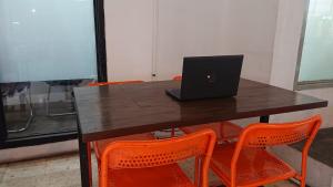 a table with orange chairs and a laptop on it at OYO Life 93139 Apartemen Grand Sentraland By Evi in Jaken 1