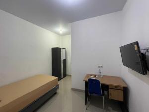 a room with a bed and a desk and a tv at Hotel O Penginapan Musafir Syariah Near Paramount Woman & Childern's Hospital in Pangkajene