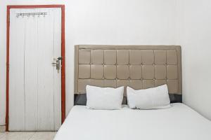 une chambre avec un lit avec des oreillers blancs dans l'établissement Hotel O Penginapan Tulimario Syariah, à Jambi