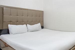 un lit blanc avec deux oreillers dessus dans l'établissement Hotel O Penginapan Tulimario Syariah, à Jambi