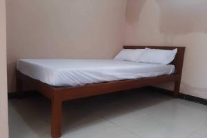 a wooden bed with white sheets and pillows on it at Hotel O Syagita Kos & Penginapan Syariah in Yogyakarta +4 photos