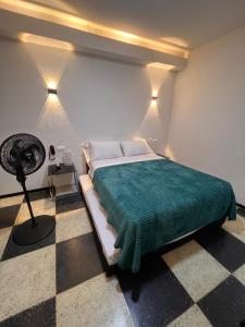 een slaapkamer met een bed met een groene deken en een ventilator bij Hotel Ensueño in Pereira