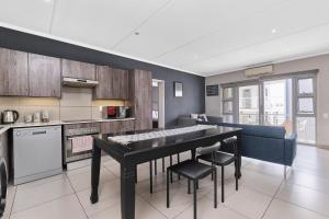 une cuisine avec une table et des chaises dans une pièce dans l'établissement Spacious 2BR Apt Minutes from Sandton City with Gym and Pool, à Johannesbourg