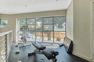 ein Fitnessstudio mit einem Laufband und einem Stuhl vor einem Fenster in der Unterkunft Modern Comfort Retreat in Central Sandton with WiFi , Gym and Pool in Johannesburg
