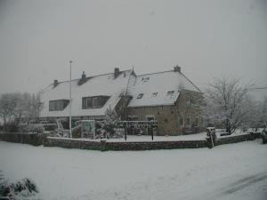 a house covered in snow in a yard at De Groede in Oosterend