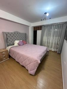 a bedroom with a bed with a pink comforter at Vale's Cottage in Huaraz +2 photos