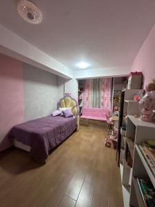 a bedroom with a bed with a purple bedspread and a pink room at Vale's Cottage in Huaraz