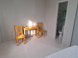 a bathroom with two wooden chairs and a table and a toilet at Melecio and sons in Carmen