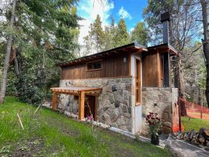 a cabin in the woods with a stone wall at LOS HUEMULES - casa nueva en medio del bosque y a pasos del centro de la ciudad- in San Carlos de Bariloche