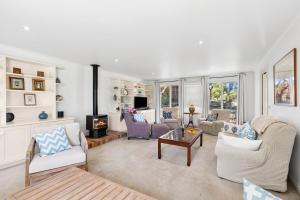 een woonkamer met witte meubels en een open haard bij Noma Escape in Queenscliff