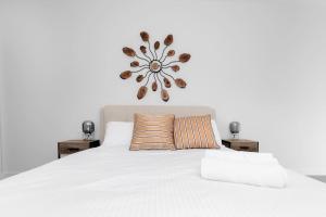 Doncaster EastSpecious 2beds Apt Doncaster east Wifi and carpark的卧室里有一张白色的床，墙上挂着一个花钟