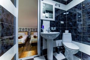 un bagno con lavandino, servizi igienici e un letto di HOTEL GUGLUX &WINE CELLAR a Telavi