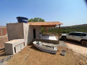 a small house with a boat in front of it at Los Arboles - Quarto com Banheiro in Alexânia +2 photos