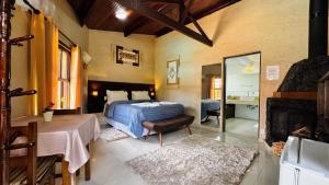 a bedroom with a bed and a fireplace at Vila Eremita Pousada in Monte Verde +43 photos