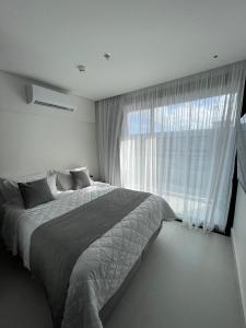 ein Schlafzimmer mit einem großen Bett und einem großen Fenster in der Unterkunft Porto alto resort in Ipojuca