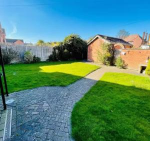 een grasveld met een bakstenen huis en een loopbrug bij Kinda Apartments in Skegness