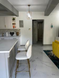 a kitchen with two white chairs and a counter at Cane Garden Bay 2 bed Apt in Leonards +3 photos