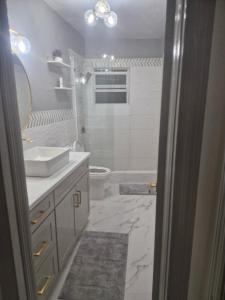 a white bathroom with a sink and a toilet at Cane Garden Bay 2 bed Apt in Leonards