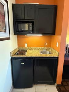 a kitchen with black cabinets and a sink at Executive Inn and Suites in Pittsburg