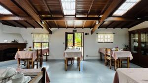 a dining room with tables and chairs and windows at Vila Eremita Pousada in Monte Verde