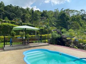 a swimming pool with a table and an umbrella at Finca Mi Fortuna - Con Piscina Privada y Vistas en La Mesa in La Mesa