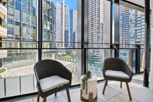 two chairs on a balcony with a view of a city at Spacious Modern Apartment with Pool & Gym Access in Melbourne