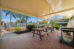 a patio with two picnic tables and a grill at Albury Holiday Park in Albury
