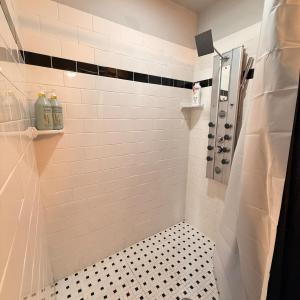 a bathroom with a shower with black and white tiles at Exposed Elegance in Mobile +40 photos