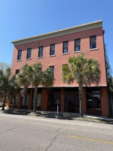 a red building with palm trees in front of it at Exposed Elegance in Mobile