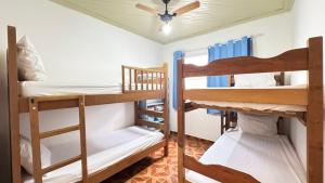 a room with two bunk beds and a ceiling fan at Casa terrea perfeita para familias 100 m da praia do Arpoador, com piscina, churrasqueira, ar condicionado e 4 quartos in Peruíbe +38 photos
