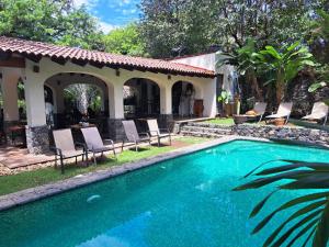 a swimming pool with chairs and a house at Hacienda Maria Elena in Tepoztlán