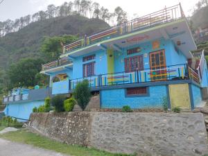 a blue house with a balcony on a hill at Peace Vibe Homestay in Uttarkāshi