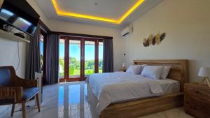 a bedroom with a bed and a chair and windows at INNerpeace Bali in Darmasaba +89 photos