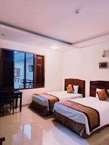 a hotel room with two beds and a window at An Thái Hotel in Kon Tum