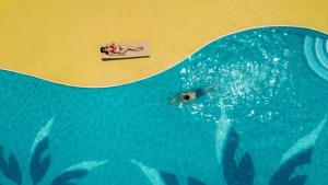 a person swimming in the water in a swimming pool at ANA InterContinental Manza Beach Resort by IHG in Onna