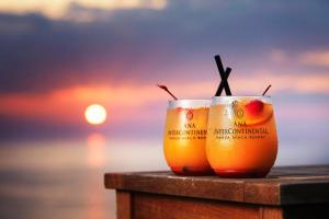 two drinks sitting on a table with the sunset in the background at ANA InterContinental Manza Beach Resort by IHG in Onna