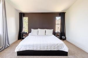 een slaapkamer met een groot wit bed met twee ramen bij Desert Escape Home with 3BD 3BA with Pool and Jacuzzi in Wildomar