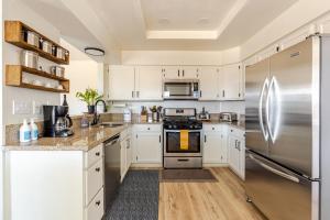a kitchen with white cabinets and a stainless steel refrigerator at Desert Escape Home with 3BD 3BA with Pool and Jacuzzi in Wildomar