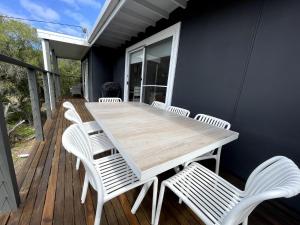 a wooden table and chairs on a deck at Surf Charm in Venus Bay