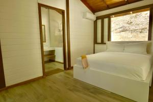 a bedroom with a white bed and a window at Villa Jimi Las Terrenas in El Naranjito