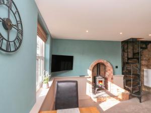 a living room with a fireplace and a clock on the wall at Top Holme Cottage in York